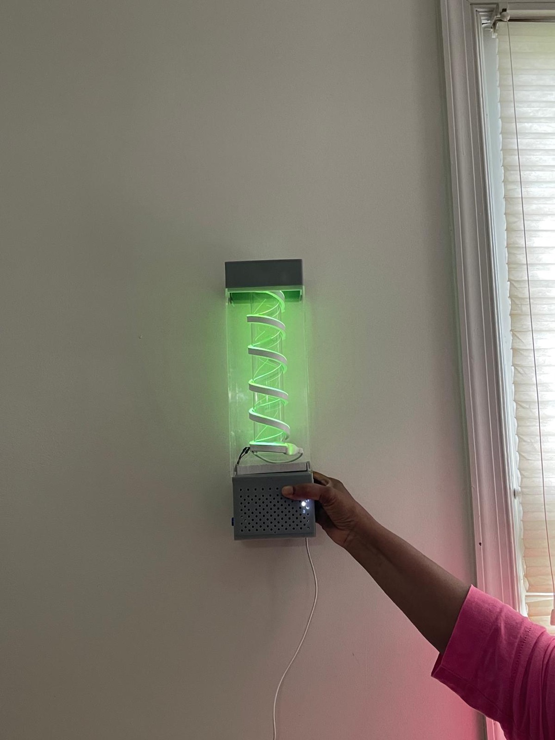 BreathPal wall-mounted prototype glowing softly, held in a hand